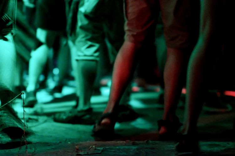 Low section of people standing at concert during night