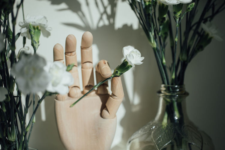 Close-up of hand holding flower vase on table