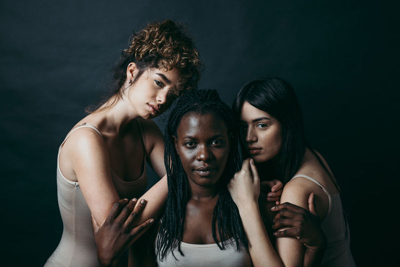 Portrait of women standing against black background