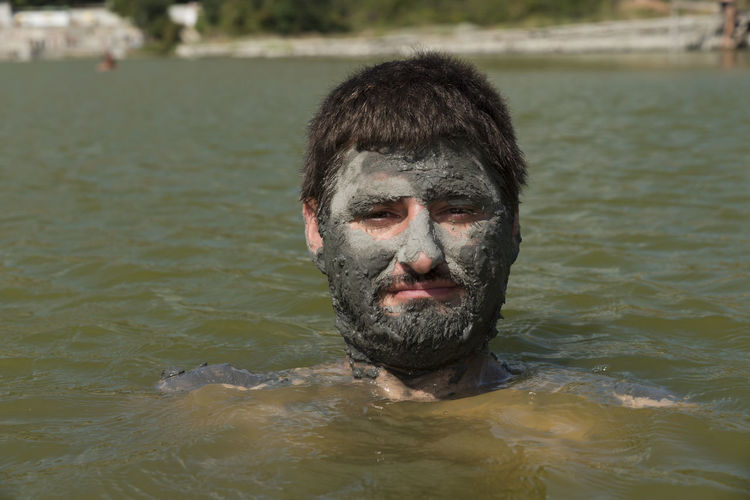 Portrait of man with mud on face in lake