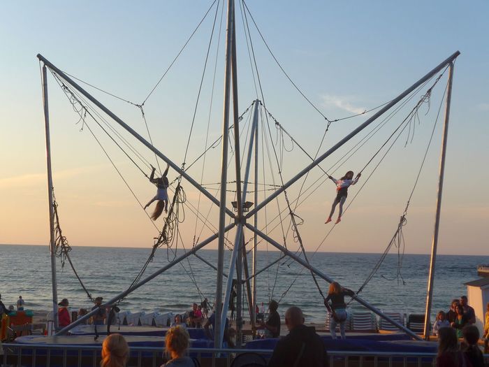 Women on bungee swings against sea