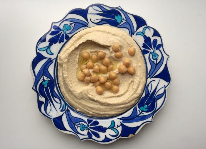 Directly above view of fresh hummus with chick-peas served in plate on white background