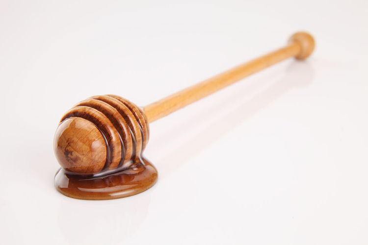 Close-up of honey dipper over white background