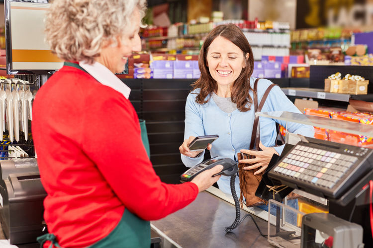 Smiling female customer paying at supermarket counter