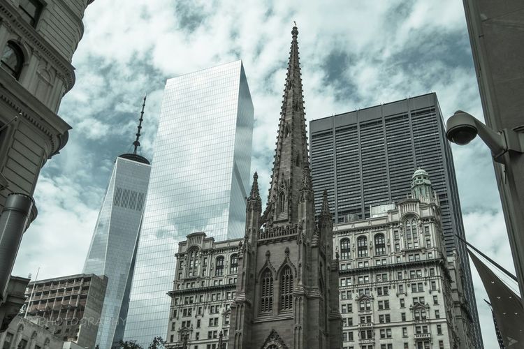 Low angle view of st patrick cathedral and one world trade center against cloudy sky