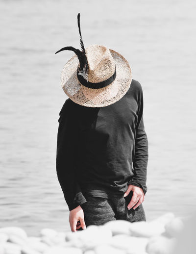 Rear view of man standing against sea with sun hat