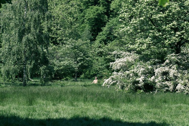 Man meditating on field during sunny day