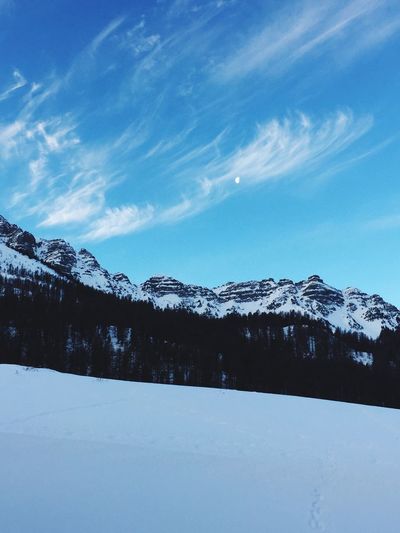 Scenic view of snow covered mountains against cloudy sky