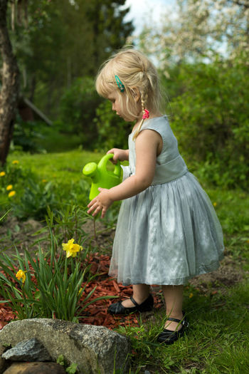 Full length of cute girl watering plants in garden