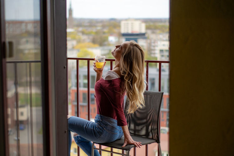 Side view of woman having drink while sitting on chair