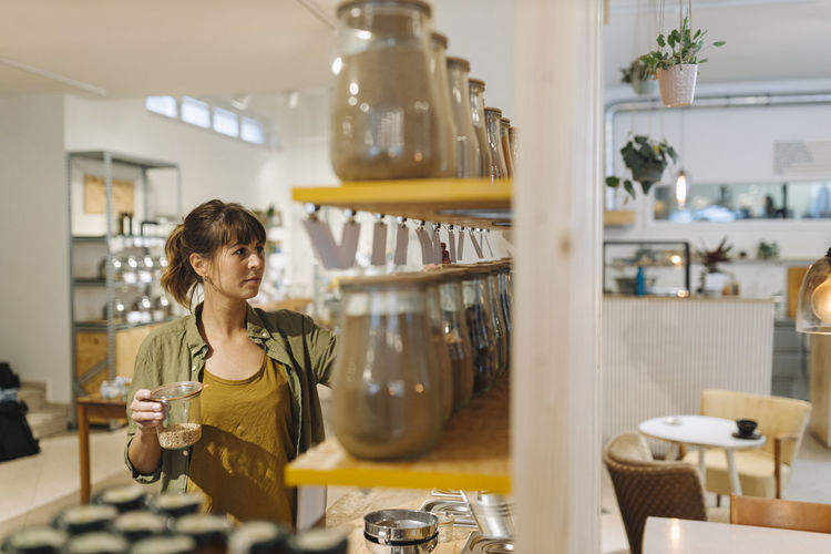 Female entrepreneur arranging glass jar in cafe
