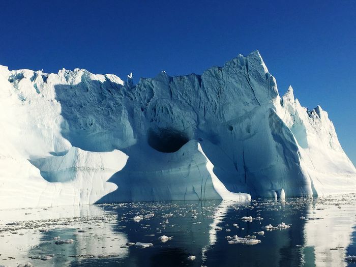 Large iceberg in sea against clear blue sky