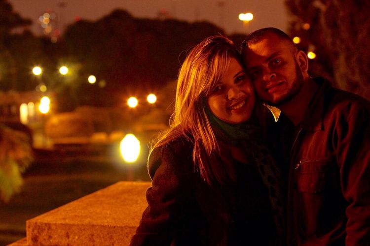 Portrait of smiling man and woman at night