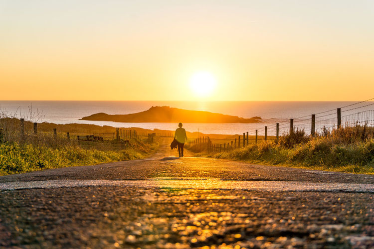 Rear view of person on road against sky during sunset