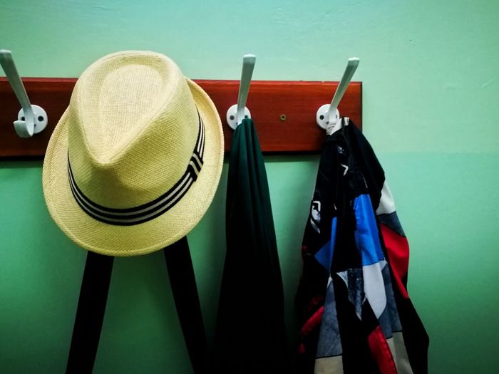 Close-up of hat hanging and clothes against wall