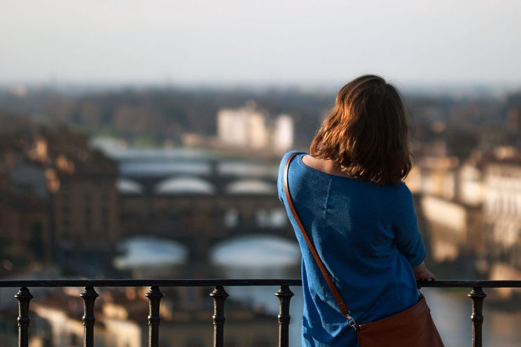 Rear view of woman standing against railing in city. italy, florence