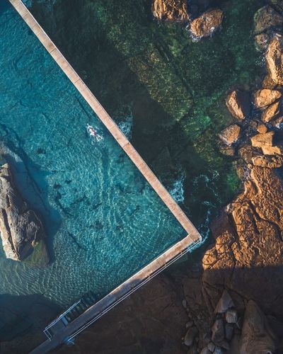 Aerial view of swimming pool at rocky coastline