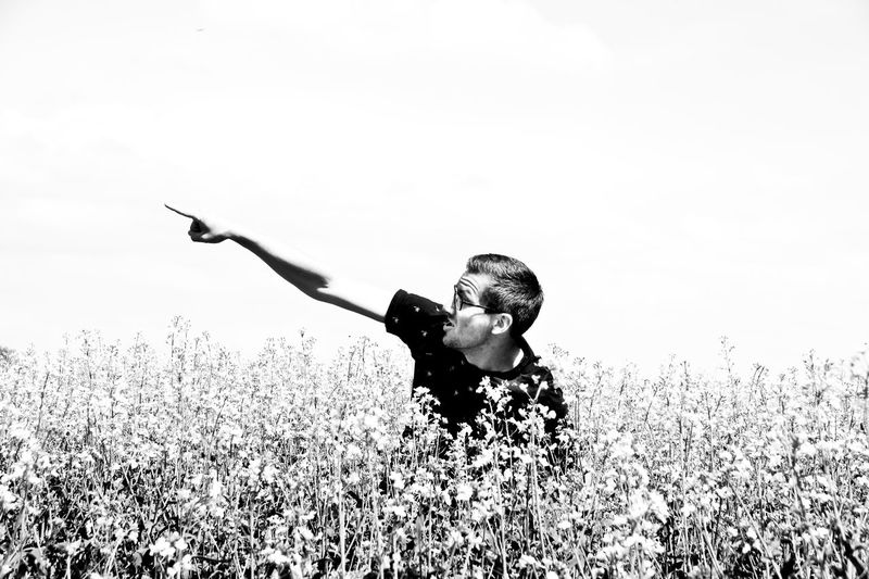 Mid adult man gesturing on oilseed rape field against clear sky