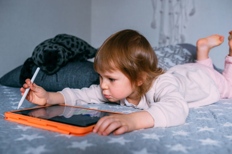 Child using technology. toddler at home with a tablet and a pen stylus and draws