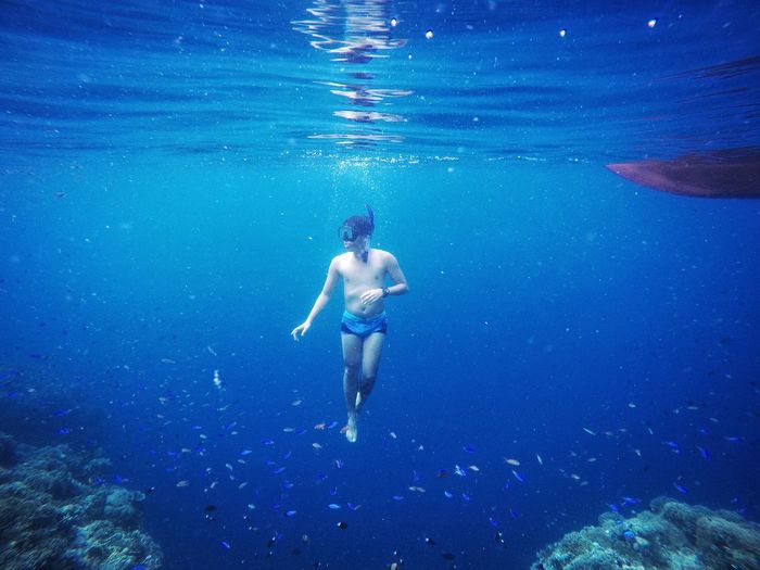 Full length of shirtless man swimming in ocean