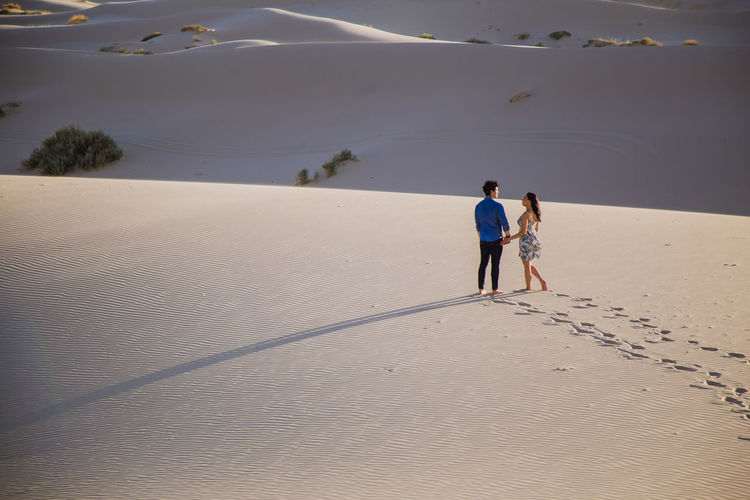 High angle view of couple walking on sand at desert