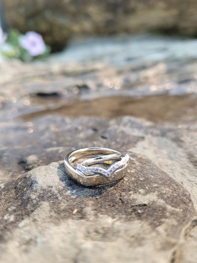 Close-up of wedding rings on rock at beach