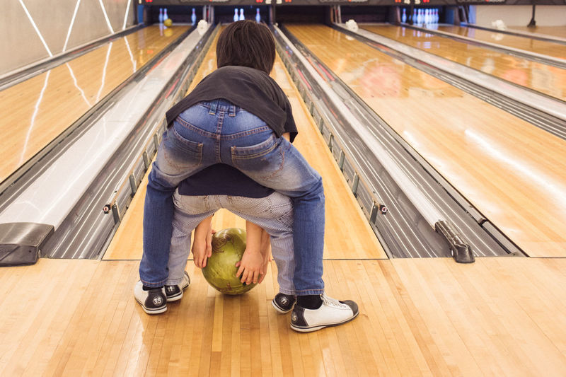 Rear view of siblings with ball in front of bowling alley