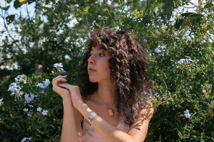 Woman with curly hair standing against sky