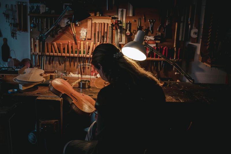 Woman making violin in darkroom