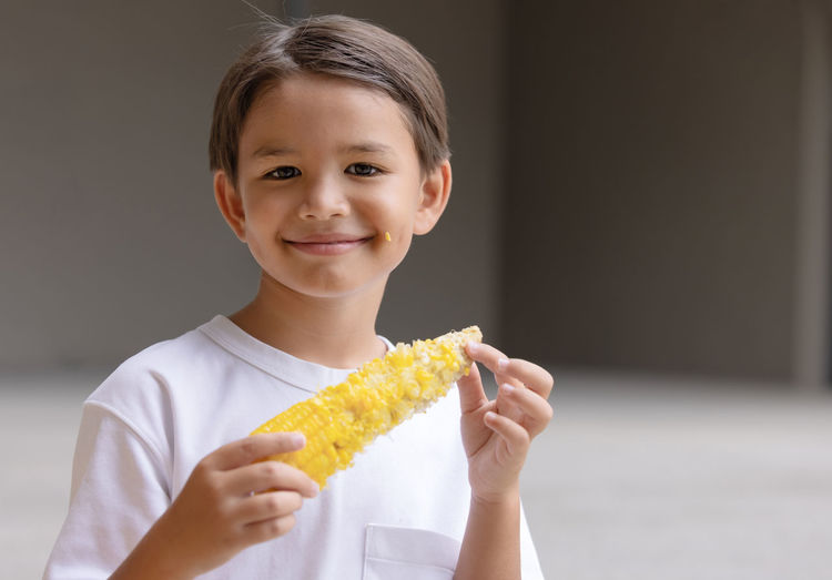 Portrait of young woman holding corn