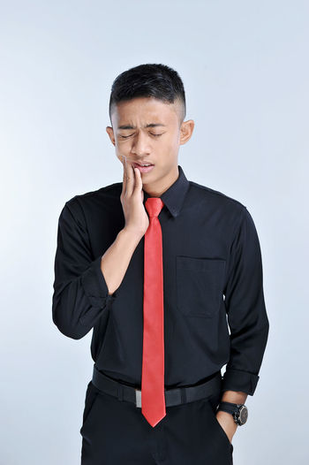 Handsome young asian business man touching mouth with hand with painful expression because of toothache or dental illness on teeth