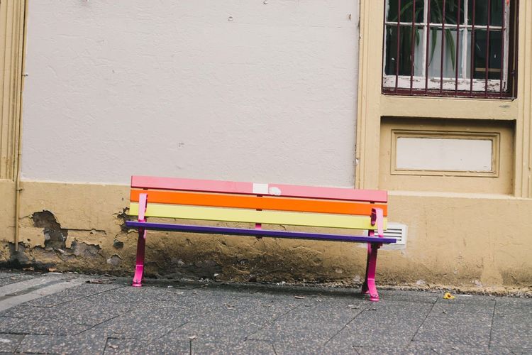Empty bench against wall in city