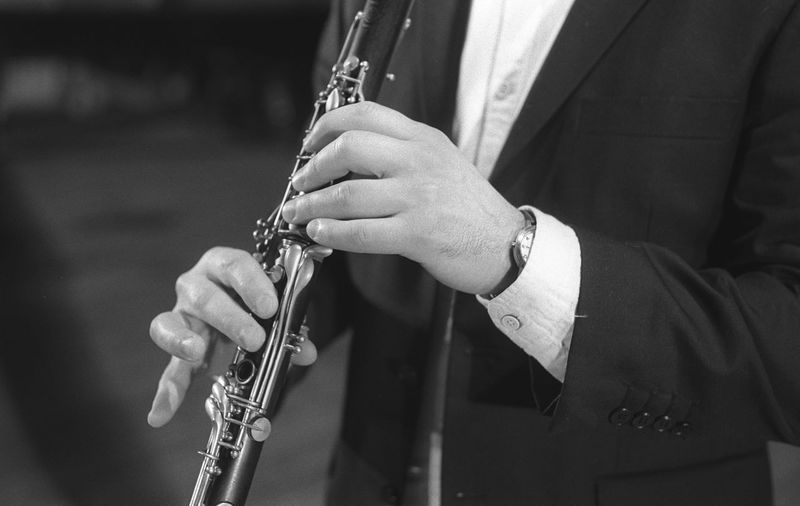 Midsection of man playing clarinet