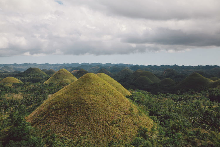 Scenic view of chocolate hills against cloudy sky