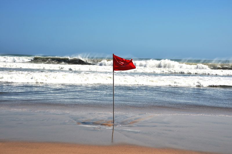 Red flag on beach against clear sky