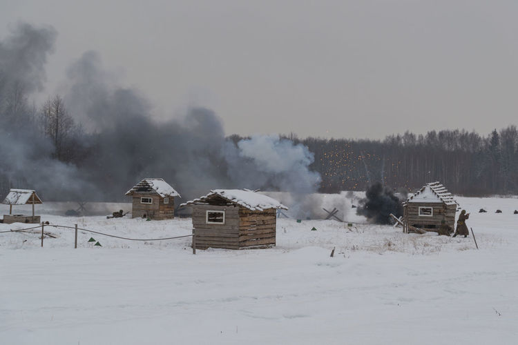 Smoke by houses on snow covered field