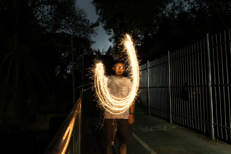 Blurred motion of man standing by illuminated light at night