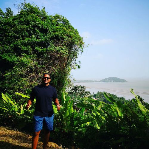 Portrait of man wearing sunglasses standing against plants