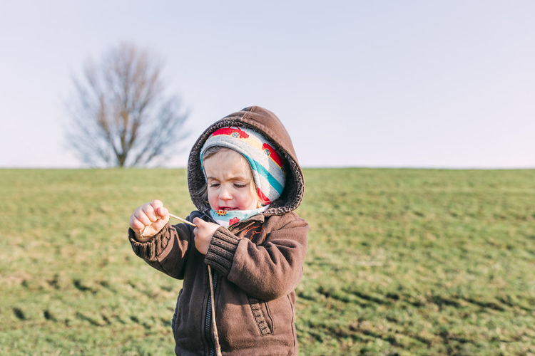 Cute girl wearing warm clothing standing on land against clear sky