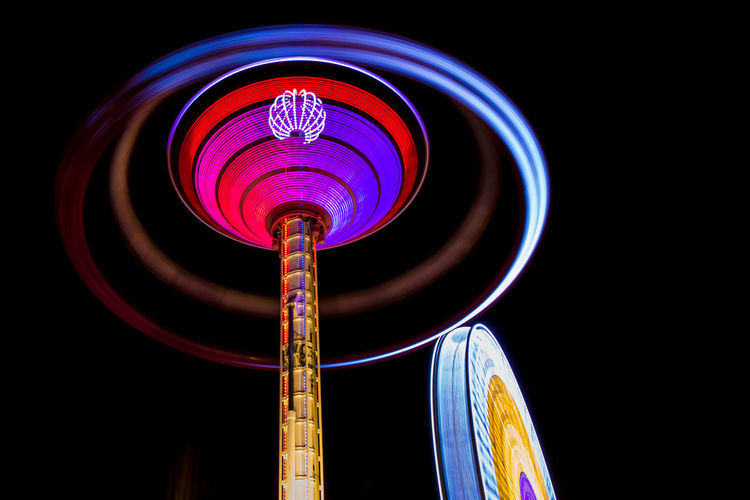 Low angle view of illuminated carousel against clear sky at night