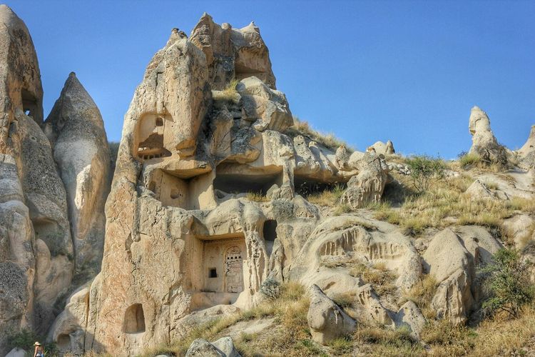 Low angle view of caves in cappadocia against clear blue sky
