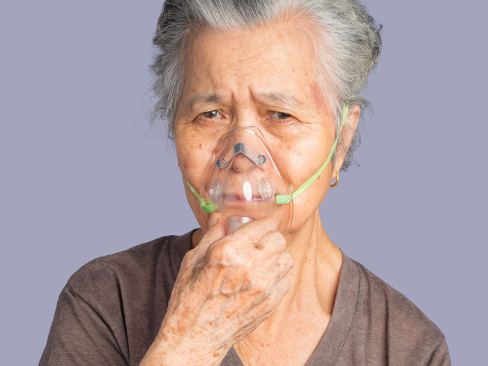 Close-up of an elderly asian woman wearing a medical breathing mask.