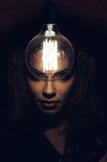 Close-up of woman in illuminated light bulb