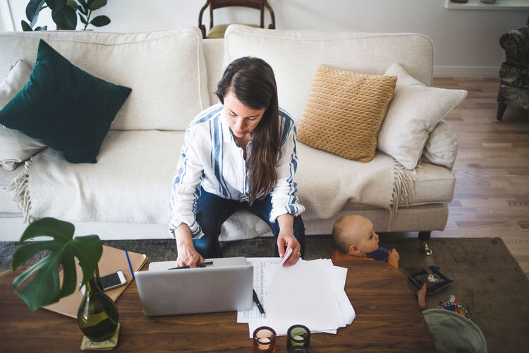 High angle view of female entrepreneur concentrating on work while daughter playing at home office