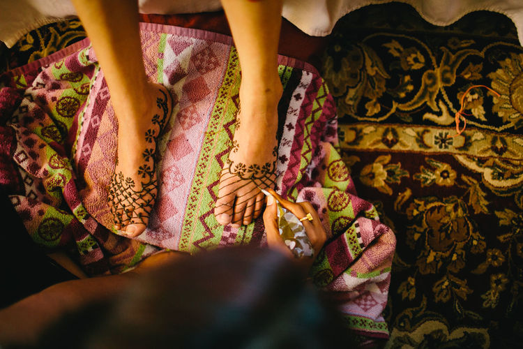 Close-up of woman tattooing leg of bride with henna