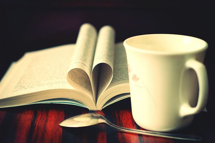 Close-up of book with coffee cup and spoon on table