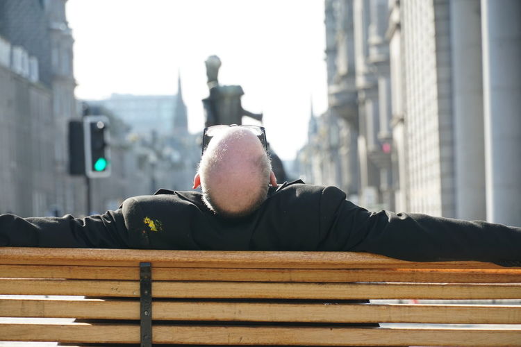 Portrait of man relaxing on bench in city