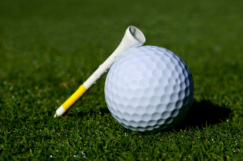 Close-up of golf ball and tee on grass