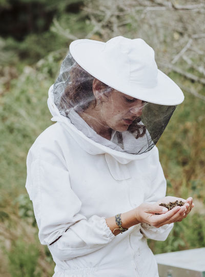 A portrait of a woman beekeeper with dead bees in the hands