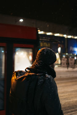 Rear view of man standing against bus at night